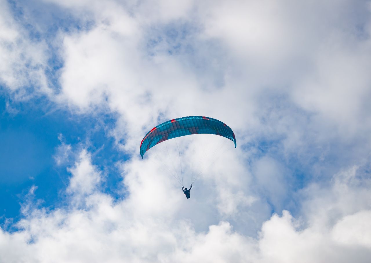 A paraglider floats effortlessly in a cloudy sky over Nepal, capturing the thrill of adventure sports.